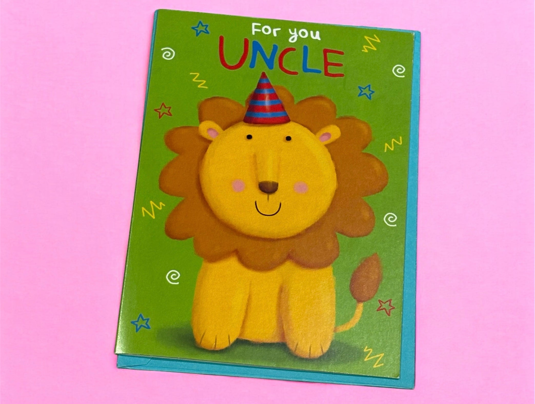 A vibrant green greeting card with an illustration of a cartoon lion wearing a colorful party hat. The text on the card reads 'For you UNCLE' with a background of blue and red stars and yellow squiggly lines.